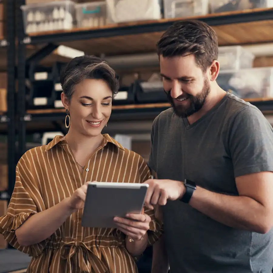 Manager and associate using a mobile device to check stock levels information in a warehouse.